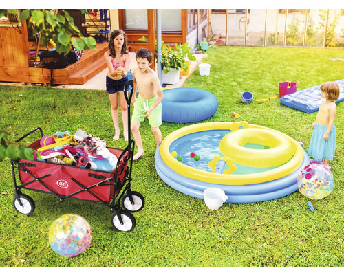 Scène de jardin avec des enfants, un chariot rempli de jouets et une pataugeoire