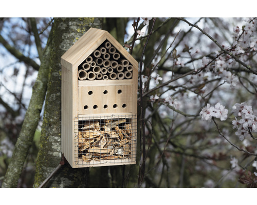 Insektenhotel aus Holz mit verschiedenen Füllmaterialien im Baum