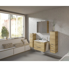Badezimmer mit Waschtisch, Spiegelschrank und Unterschränken in hellem Holzdekor vor einer Wand mit Fischgrätmuster