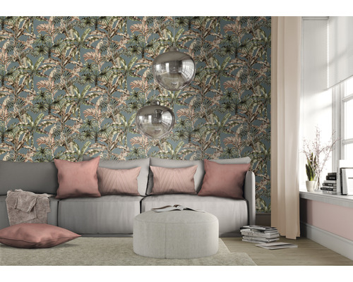 Salon avec canapé, coussins et décoration devant un papier peint à motif de plantes