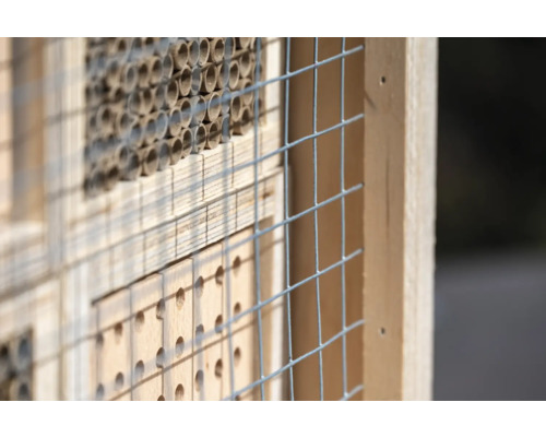 Nahaufnahme eines Insektenhotels mit Bambusröhren und Drahtgitter