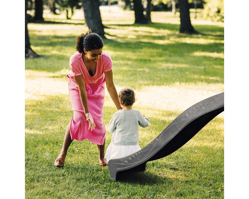 Mutter und Kind mit Kinderrutsche im Garten