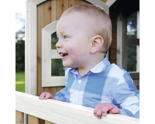 Enfant souriant dans une cabane de jeu en bois