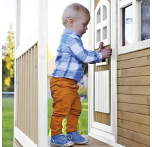 Jeune enfant debout devant une cabane de jeu en bois avec porte