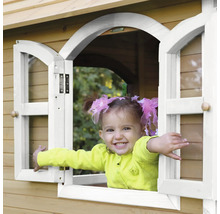 Enfant souriant à la fenêtre d''une cabane de jeu en bois