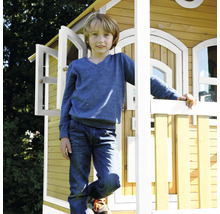 Garçon devant une cabane de jeu en bois dans le jardin