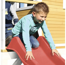 Enfant glissant sur un toboggan rouge sur une cabane de jeu