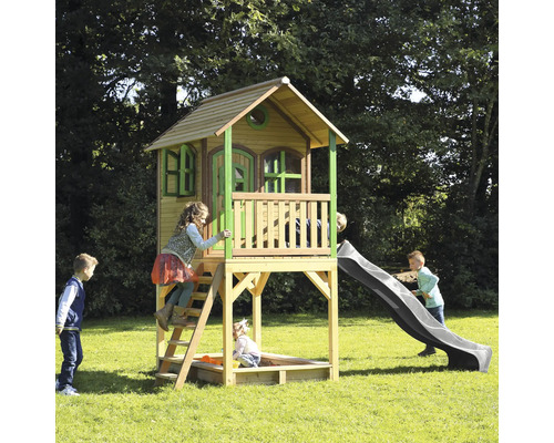 Kinderspielhaus mit Rutsche und Sandkasten im Garten mit spielenden Kindern.