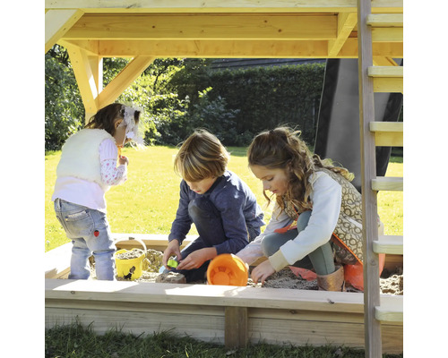 Kinder spielen im Sandkasten unter einem Spielturm