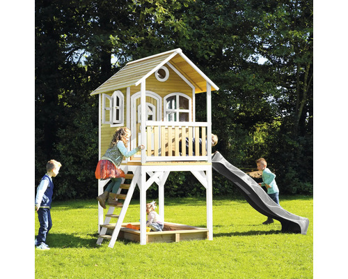 Maison de jeu en bois avec toboggan et bac à sable dans le jardin avec des enfants qui jouent