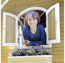 Un enfant regarde par la fenêtre d''une cabane en bois avec jardinière