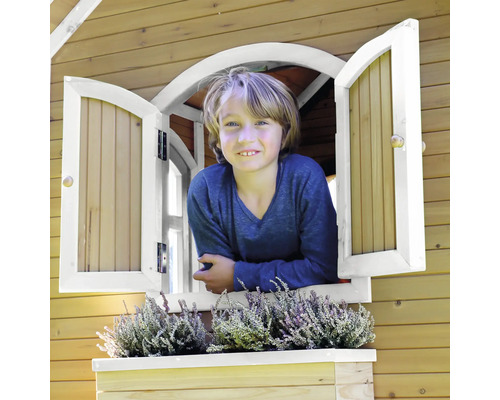 Un enfant regarde par la fenêtre d''une cabane en bois avec jardinière