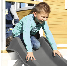 Garçon glissant sur un toboggan sur une maison de jeux