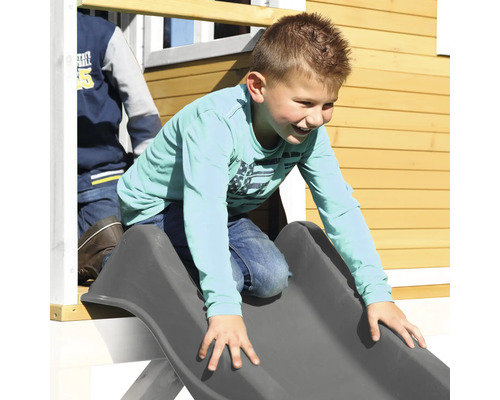 Garçon glissant sur un toboggan sur une maison de jeux