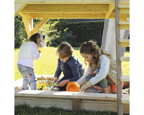 Kinder spielen im Sandkasten unter einem Spielturm