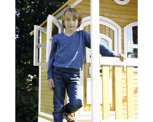 Garçon devant une cabane en bois avec fenêtres ouvertes