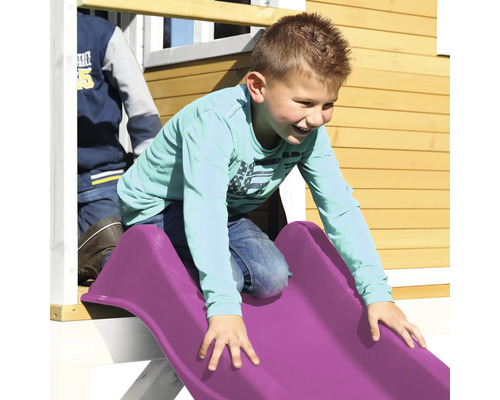 Garçon glissant sur un toboggan de terrain de jeu en plastique.