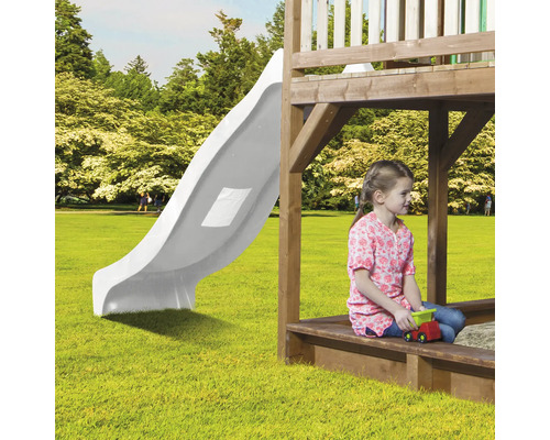 Kind auf einem Spielplatz mit Rutsche und Sandkasten.