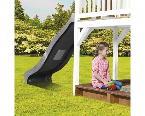 Spielturm mit Rutsche und Sandkasten im Garten mit spielendem Kind