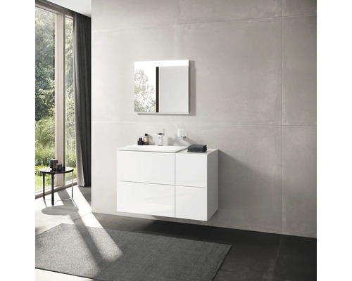 Badezimmer mit weißem Waschtischunterschrank, Spiegel und großformatigen Fliesen.