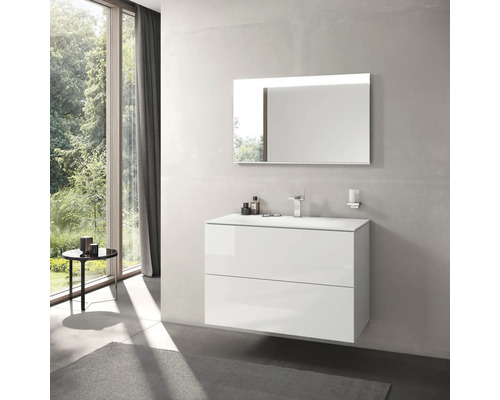 Salle de bains moderne avec meuble-lavabo blanc, miroir avec éclairage et fenêtre donnant sur la verdure