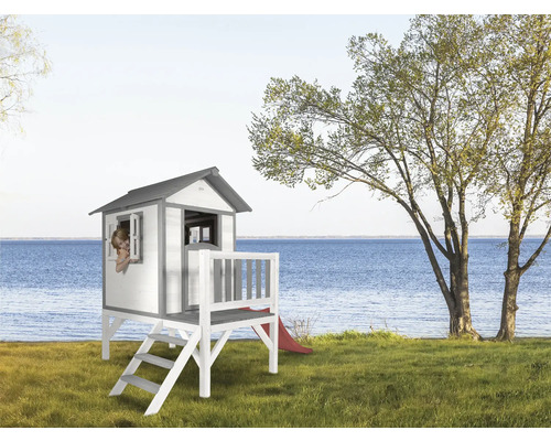 Maison de jeux en bois avec escalier et toboggan dans le jardin avec vue sur le lac