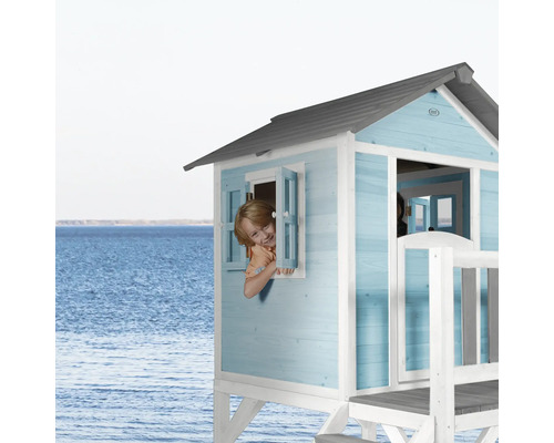 Un enfant regarde par la fenêtre d''une cabane de jeu bleue et blanche sur la plage