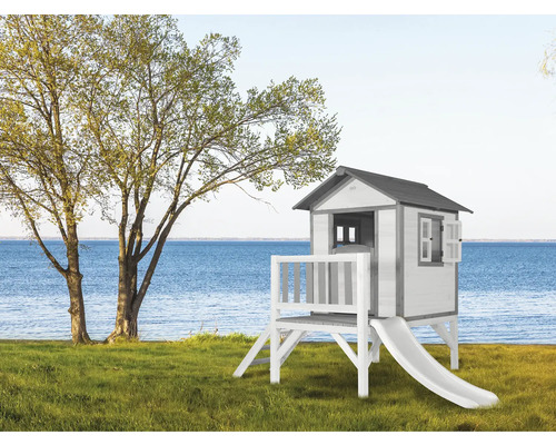 Spielhaus mit Rutsche auf einer grünen Wiese mit Blick auf das Wasser