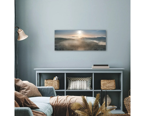 Wohnzimmer mit Wandbild, das eine verschneite Waldlandschaft im Nebel zeigt.