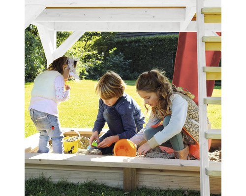 Kinder spielen im Sandkasten eines Spielturms im Garten.