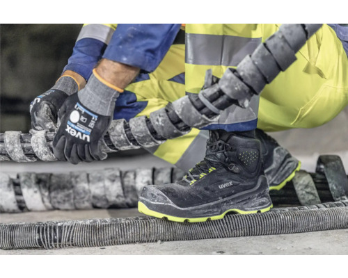 Artisan portant des chaussures de sécurité Uvex et des gants de travail au travail