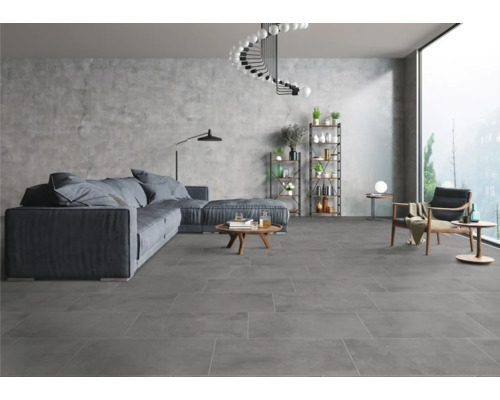 Heller Wohnraum mit grauen Bodenfliesen, Sofa, Sesseln und Regalen