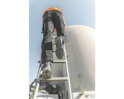 Eine Person in Arbeitskleidung steigt eine Leiter an einer Baustelle hoch