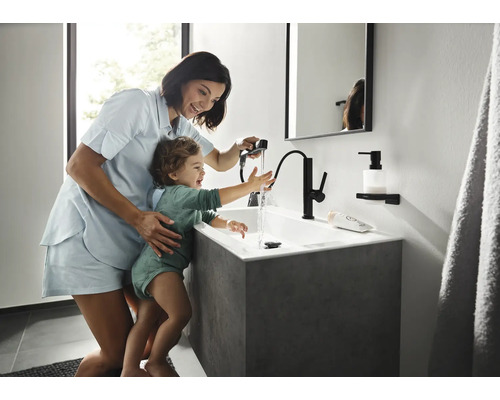 Mutter mit Kind am Waschbecken mit Armatur im Badezimmer