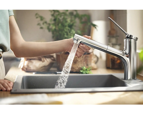 Femme utilisant un robinet en métal au-dessus d''un évier dans la cuisine