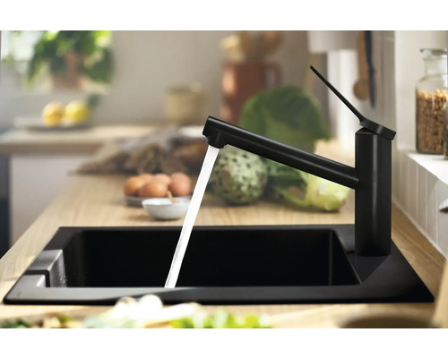 Schwarze Küchenarmatur mit laufendem Wasser in einem schwarzen Spülbecken.