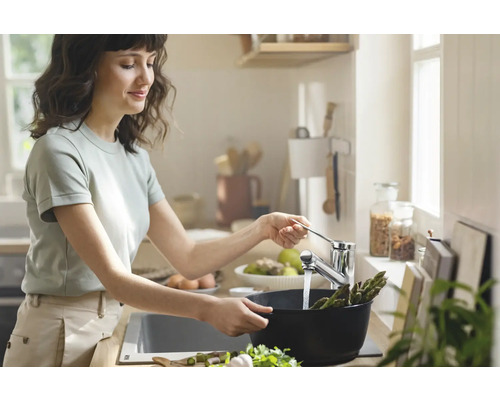 Frau wäscht Spargel in der Küche mit Küchenarmatur