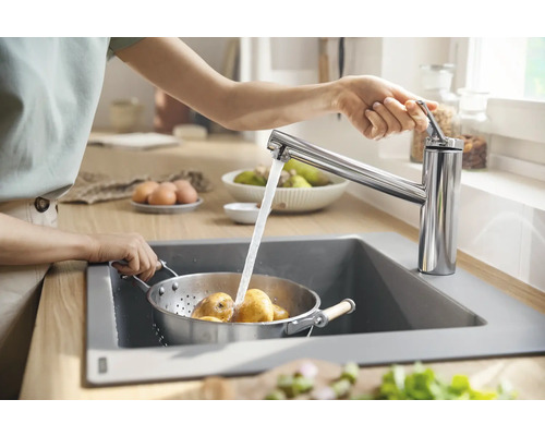 Frau wäscht Kartoffeln in einem Küchensieb unter einem Wasserhahn