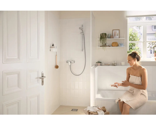 Salle de bain lumineuse avec douche, baignoire et une femme avec une serviette