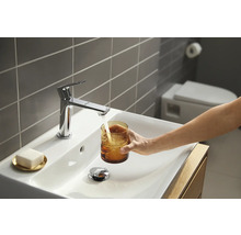 Modernes Badezimmer mit Aufsatzwaschbecken, Armatur und Person, die ein Glas Wasser befüllt