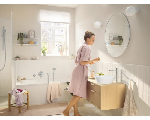 Salle de bains lumineuse avec meuble-lavabo, vasque à poser, robinetterie, miroir et baignoire.