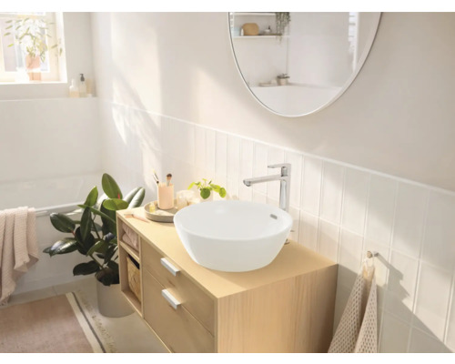 Salle de bain lumineuse avec lavabo sur meuble bas en bois, robinetterie et miroir