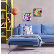 Wohnzimmer mit blauem Sofa, gelbem Regal und Wandbildern