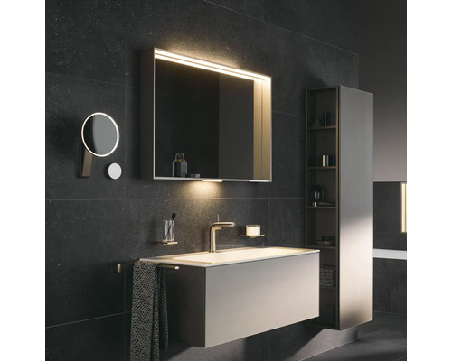 Badezimmer mit Waschtisch, Spiegelschrank mit Beleuchtung, Kosmetikspiegel und Hochschrank für Badezimmerutensilien.