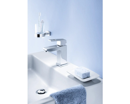 Lavabo de salle de bain avec robinet, savon, porte-savon, serviette, gobelet à brosse à dents et brosse à dents.