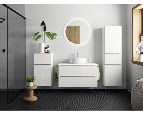 Salle de bain lumineuse avec meuble-lavabo blanc, armoire de toilette et armoire haute devant un sol sombre