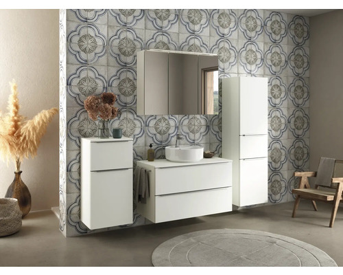 Badezimmer mit Waschbecken, Spiegel, Schrank und floral gemusterten Fliesen