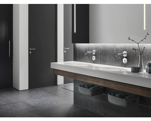 Modernes Badezimmer mit Doppelwaschbecken, Wandarmaturen, grauen Fliesen und Türen.