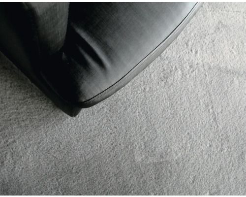 Detailaufnahme eines schwarzen Sofas auf einem hellen Teppich