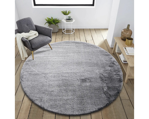 Tapis rond gris dans un salon avec fauteuil et table d''appoint.